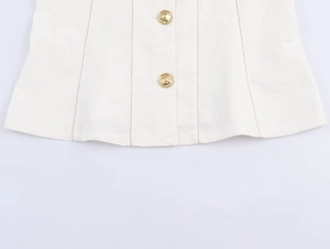 Détail macro du tissu blanc avec boutons dorés et surpiqûres marron contrastées