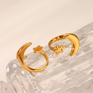 Detailed close-up of adjustable gold star and moon ring on a glass textured surface