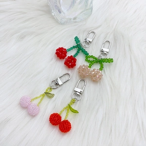 Simpatici portachiavi a ciliegia in rosso e rosa su sfondo morbido in peluche bianco