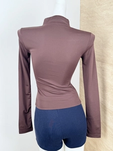 Rear view of tight-fitting long sleeve yoga top in dark brown with matte stretch fabric