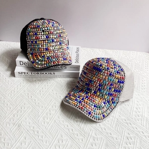 Close-up of handmade baseball caps with colorful pearls and rhinestones on mesh fabric