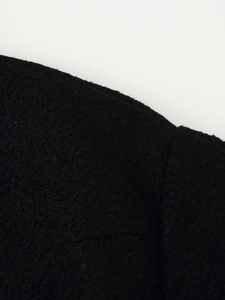 Close-up of black wool fabric texture and stitching detail on a women winter coat