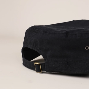 Detail of vintage black flat top military cap with copper buckle and distressed fabric