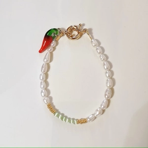 Detail of baroque pearl bracelet with cat-eye stones and a red chili pepper charm