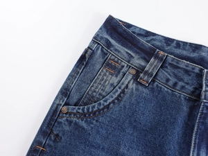 Detail of vintage low-waist jeans showing orange stitching and engraved metal button