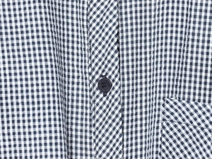 Detail of black and white gingham shirt fabric with texture and a single black button