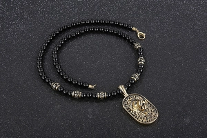 Detailed view of an embossed gold lion head pendant on black beaded long necklace