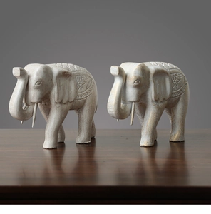 Détail de deux statuettes d'éléphants blanc ivoire avec motifs dorés sur bois massif