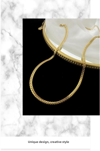 Detailed view of golden flat curb chain necklace on silk featuring a secure lobster clasp