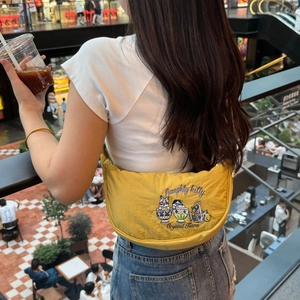 Detail of yellow dumpling bag with embroidered naughty cats shown in a casual lifestyle setting