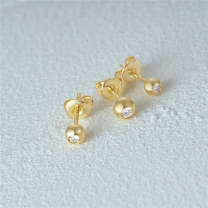 Macro shot of three gold s925 silver stud earrings with clear zircon stones and butterfly backs