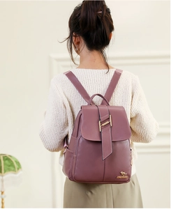 Close-up of pink pebbled leather backpack with gold kangaroo logo and metal buckle