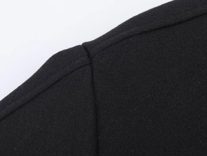 Close-up of black woolen coat shoulder showing premium fabric texture and neat stitching