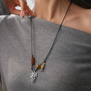 Détail du collier fait main avec perles en céramique et pendentif de raisin argenté