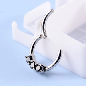 Close-up of silver stainless steel piercing ring with three black round zircon gemstones
