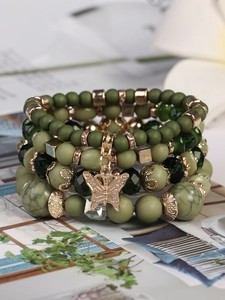 Detail eines mehrlagigen Boho-Perlenarmbands mit grünen Kristallen und Gold-Schmetterling