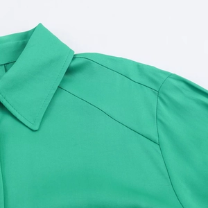 Detailed view of emerald green satin shirt featuring classic collar and fine woven texture