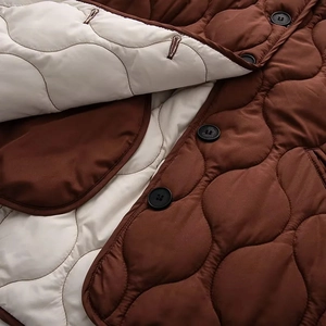 Détail d'une veste matelassée avec tissu marron, doublure blanche et boutons noirs