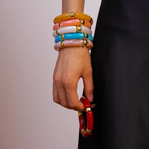 Gros plan de bracelets géométriques en acrylique coloré avec perles dorées au poignet