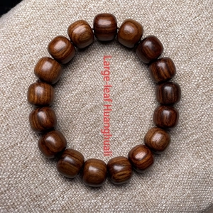 Deep brown Dalbergia retusa wood barrel bead bracelet on textured linen background