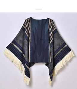Close-up of ethnic geometric jacquard knit poncho with long tassel hem in navy and coffee