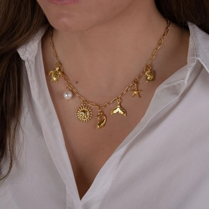 Golden paperclip necklace with shell and starfish pendants on a model wearing a white shirt