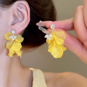 Dettaglio di orecchini a fiore giallo con perle e cristalli sull'orecchio della modella