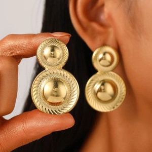 Macro detail of large gold geometric earrings with hammered texture and sunburst patterns