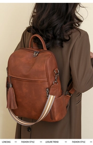 Rear view of model wearing a vintage brown PU leather backpack with tassel and striped strap