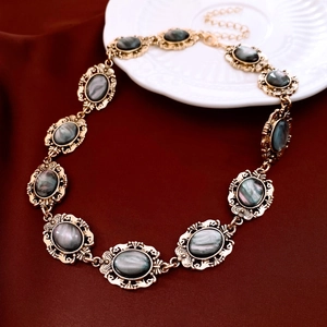 Detailed close-up of vintage gold necklace with dark resin oval pendants on red fabric