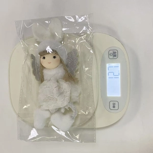 White plush angel doll with rabbit ears and wings being weighed on a scale for size