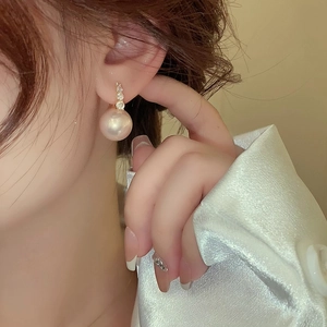 Elegant gold pearl earrings with vertical zircon accents shown on a model