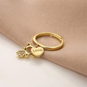 Detailed close-up of a golden adjustable ring with heart and girl charms on knit fabric