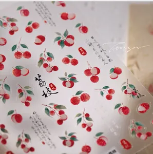 Macro detail of lychee nail art stickers featuring Chinese calligraphy and fruit patterns