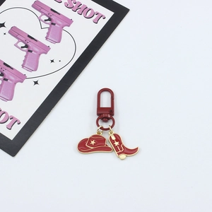 Detail of red cowboy hat and boot keychain with gold star patterns and D-ring buckle