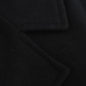 Detailed view of the elegant black wool coat lapel with thick premium texture