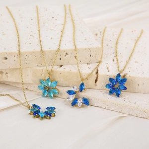 Detailed view of gold chain necklaces with blue and clear faceted floral stone pendants
