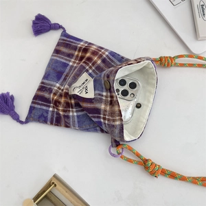 Detailed top view of purple plaid phone bag with tassels and woven rope strap