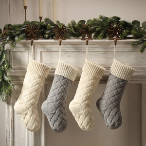 Close-up of cable knit Christmas stockings in ivory and grey on festive mantel decor
