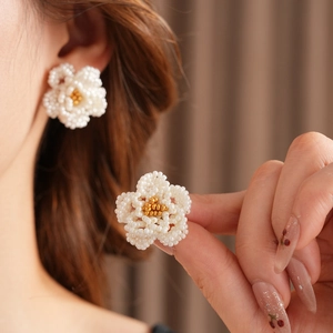 Detailed close-up of French vintage camellia earrings with white pearls and gold flower centers