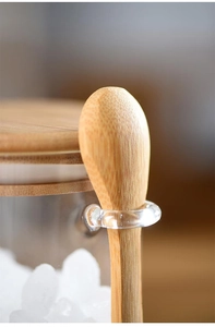 Close-up of glass storage jar with a bamboo lid and spoon inserted in the side ring
