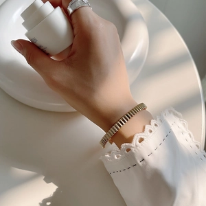Close-up of golden irregular textured bangle with pleated vertical ridges for women