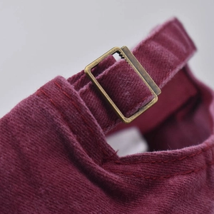 Détail de la casquette bordeaux avec boucle de réglage en métal bronzé classique