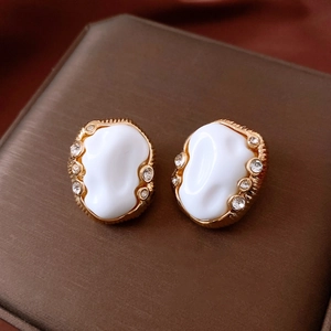 Macro detail of vintage oval gold earrings with white resin and sparkling rhinestones