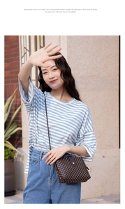 Close-up of a brown crossbody bucket bag with geometric print on a casual striped t-shirt