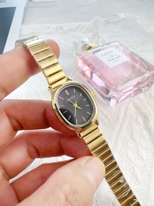 Detail shot of elegant oval black dial watch with gold alloy chain strap on wrist