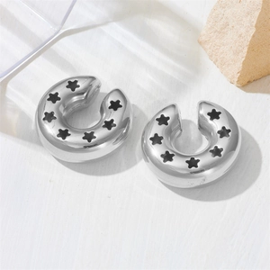 Close-up of silver stainless steel C-hoop earrings with black engraved star patterns
