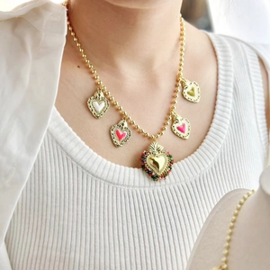 Collana di perle dorate con ciondoli a cuore in smalto colorato su gilet bianco