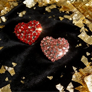 Luxury heart-shaped brooches with sparkling red and pink crystals on black velvet background