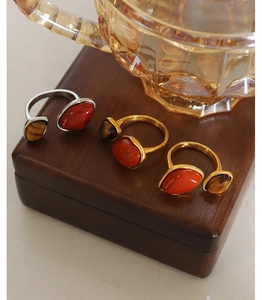 Detailed view of vintage rings featuring natural red jasper and tiger eye on a wood base